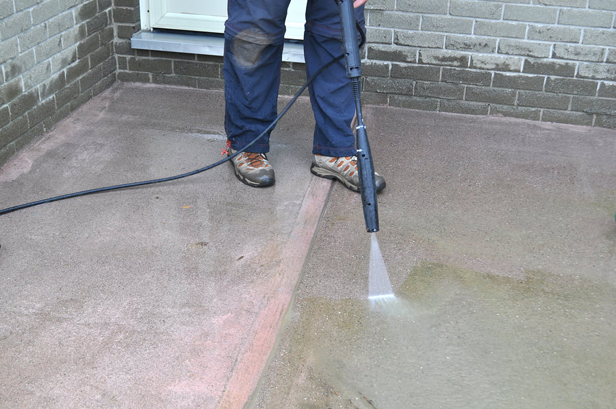 a man uses water pressure to clean the concrete floor